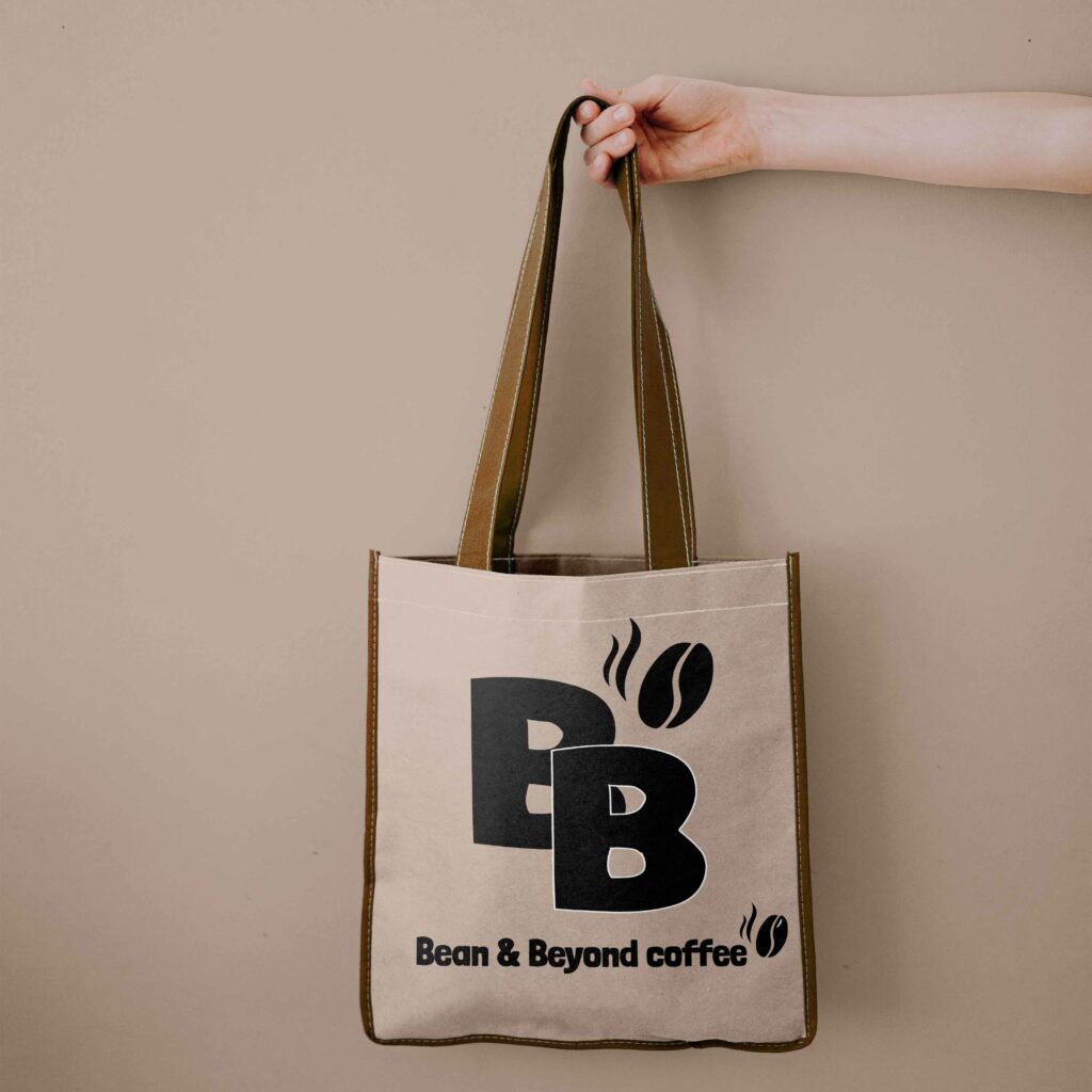 Une main de femme tient un sac style sac de course, beige avec un logo en son centre.